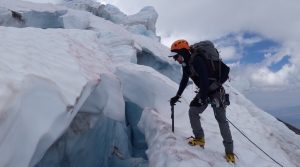 Climber peering into crevasse
