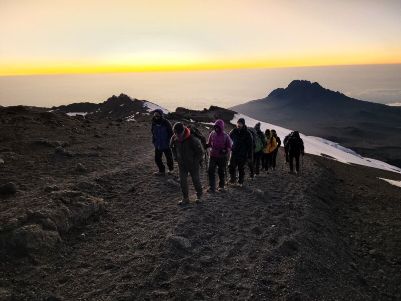 Clients hiking up Kilimanjaro at sunrise during a guided Kilimanjaro Expedition with Alpenglow Expeditions.