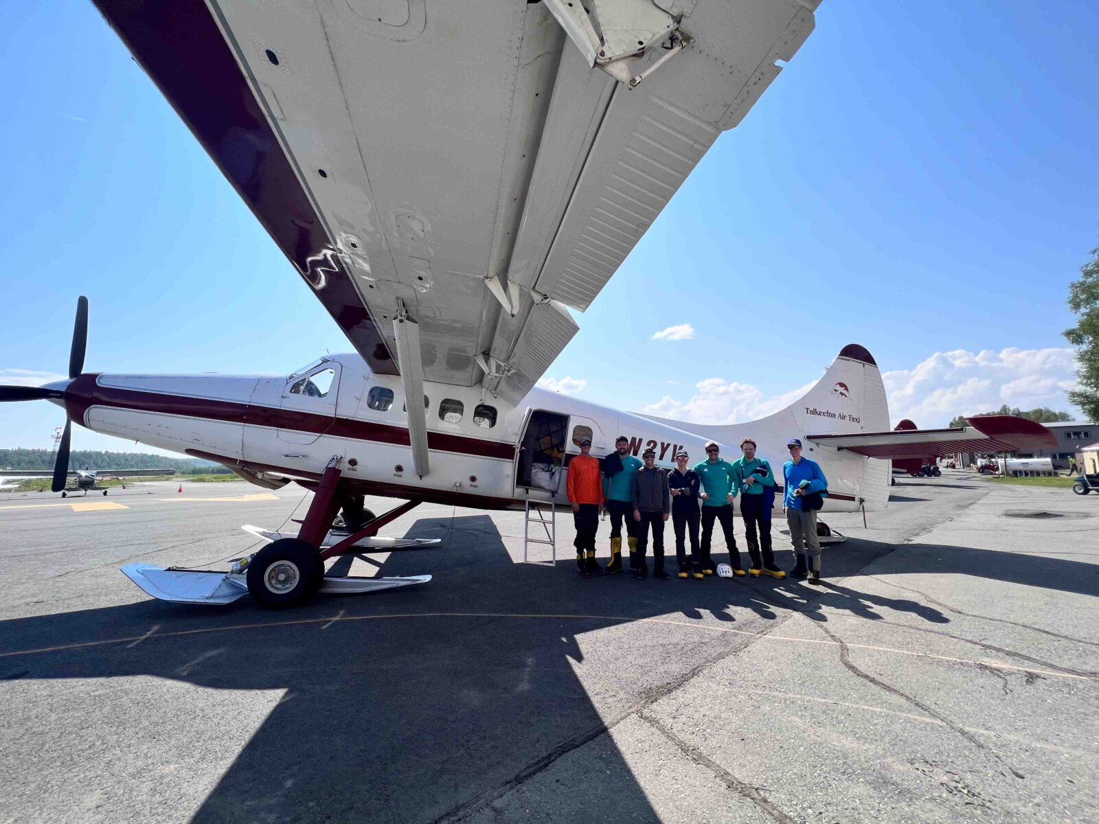 Clients posing in front of a propeller plane before their Denali Expedition