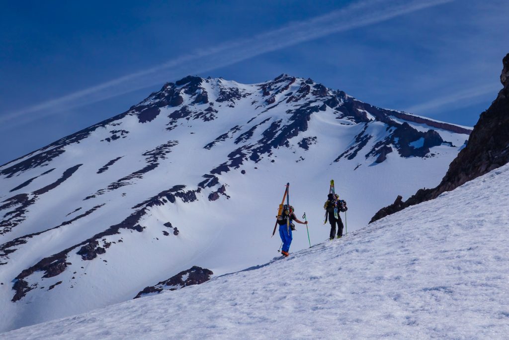Skiers climb with West face of Mount Shasta