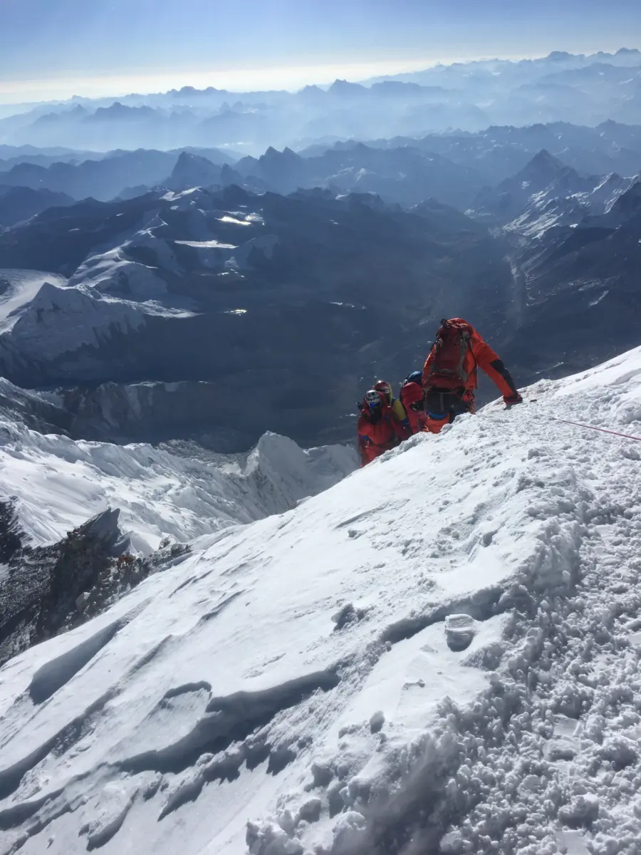 Climber on the summit of Mount Everest during an Alpenglow Expeditions guided expedition