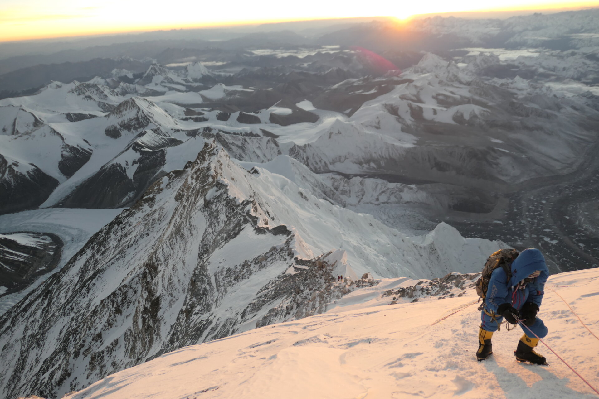 Topo Mena climbing toward the summit of Mt. Everest with the sun rising behind him over the Himalaya.
