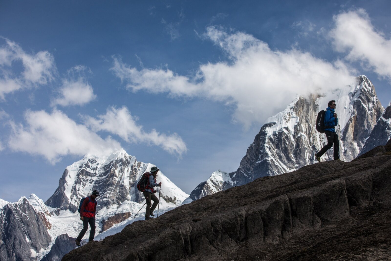 Three hikers on the Cordillera Huayhuash Trek with stunning peaks on the mountain