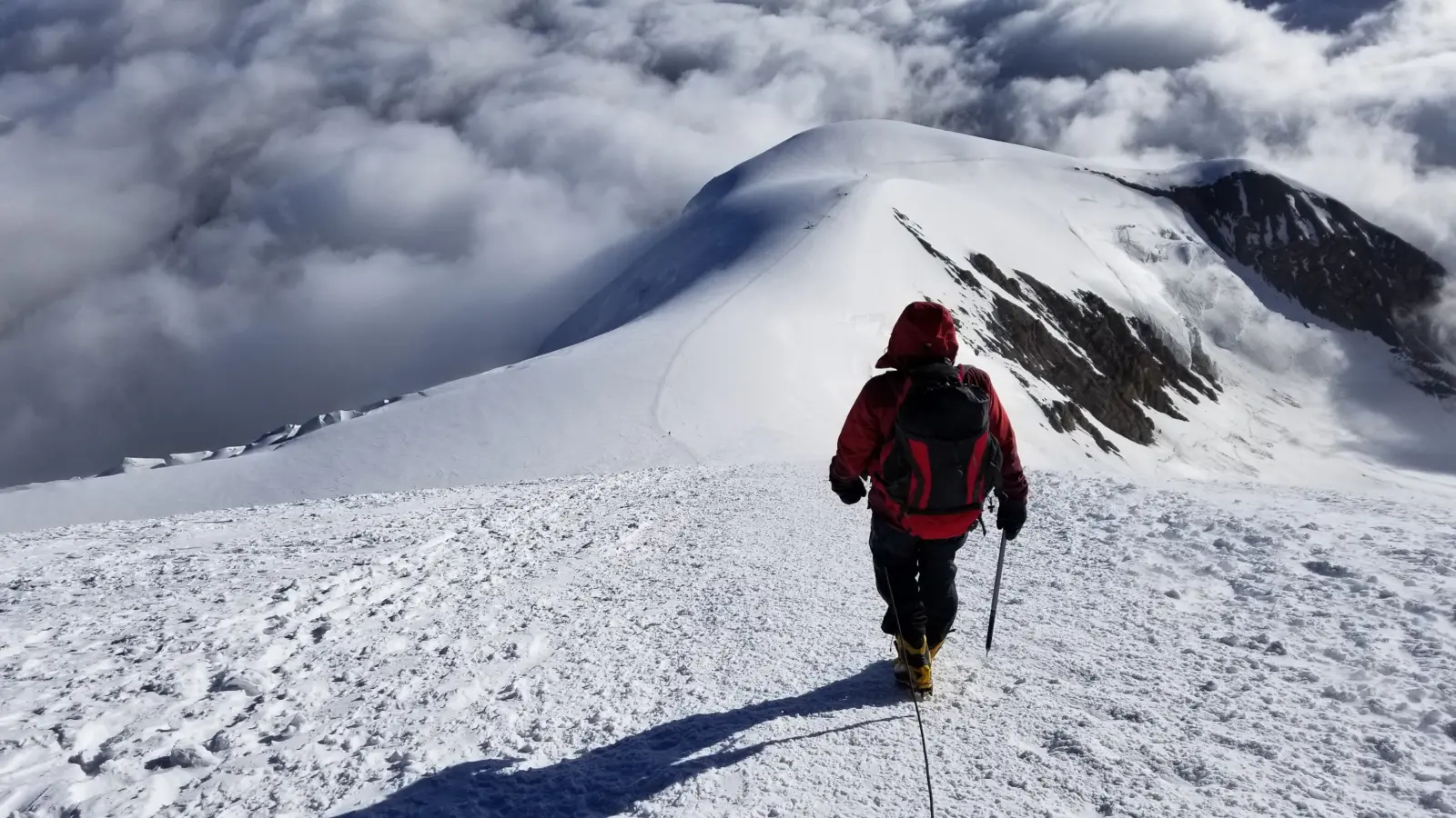 Client hiking up a ridge on a guided Peak Lenin Expedition with Alpenglow Expeditions.