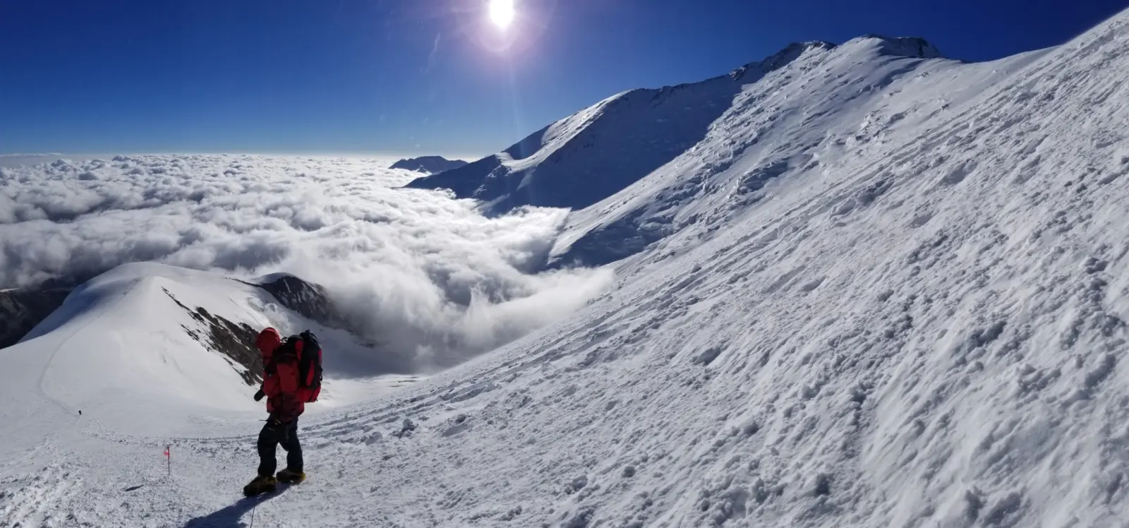 Client hiking a glaciated slope on a guided Peak Lenin Expedition with Alpenglow Expeditions.