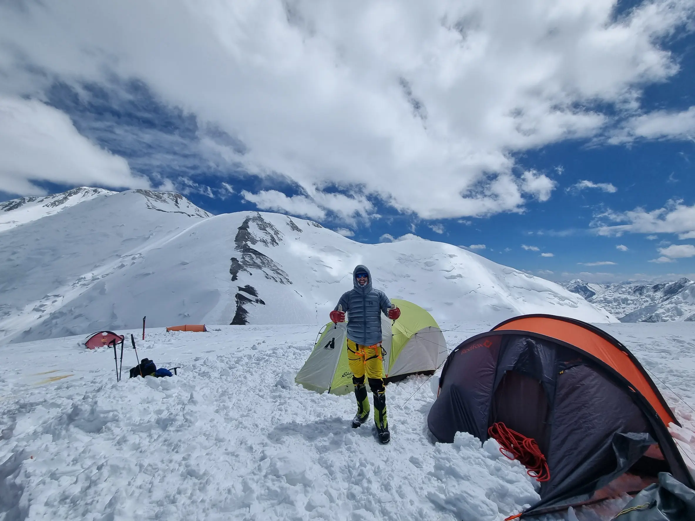 Client standing in front of a tent on a guided Peak Lenin Expedition with Alpenglow Expeditions.