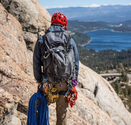 Alpenglow Expeditions' guide standing on rock ledge with trad climbing gear in Lake Tahoe.