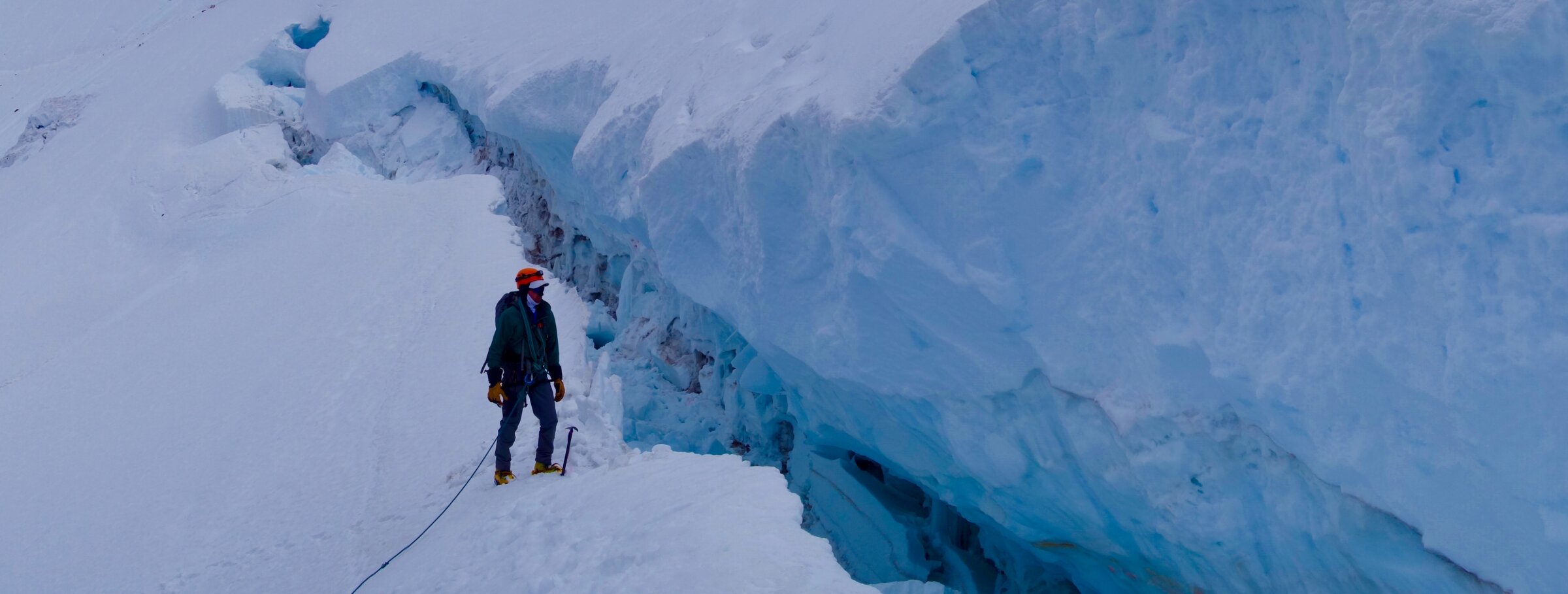 A mountaineering client standing next to a crevasse during a guided Avalanche Gulch climb on Mount Shasta with Alpenglow Expeditions