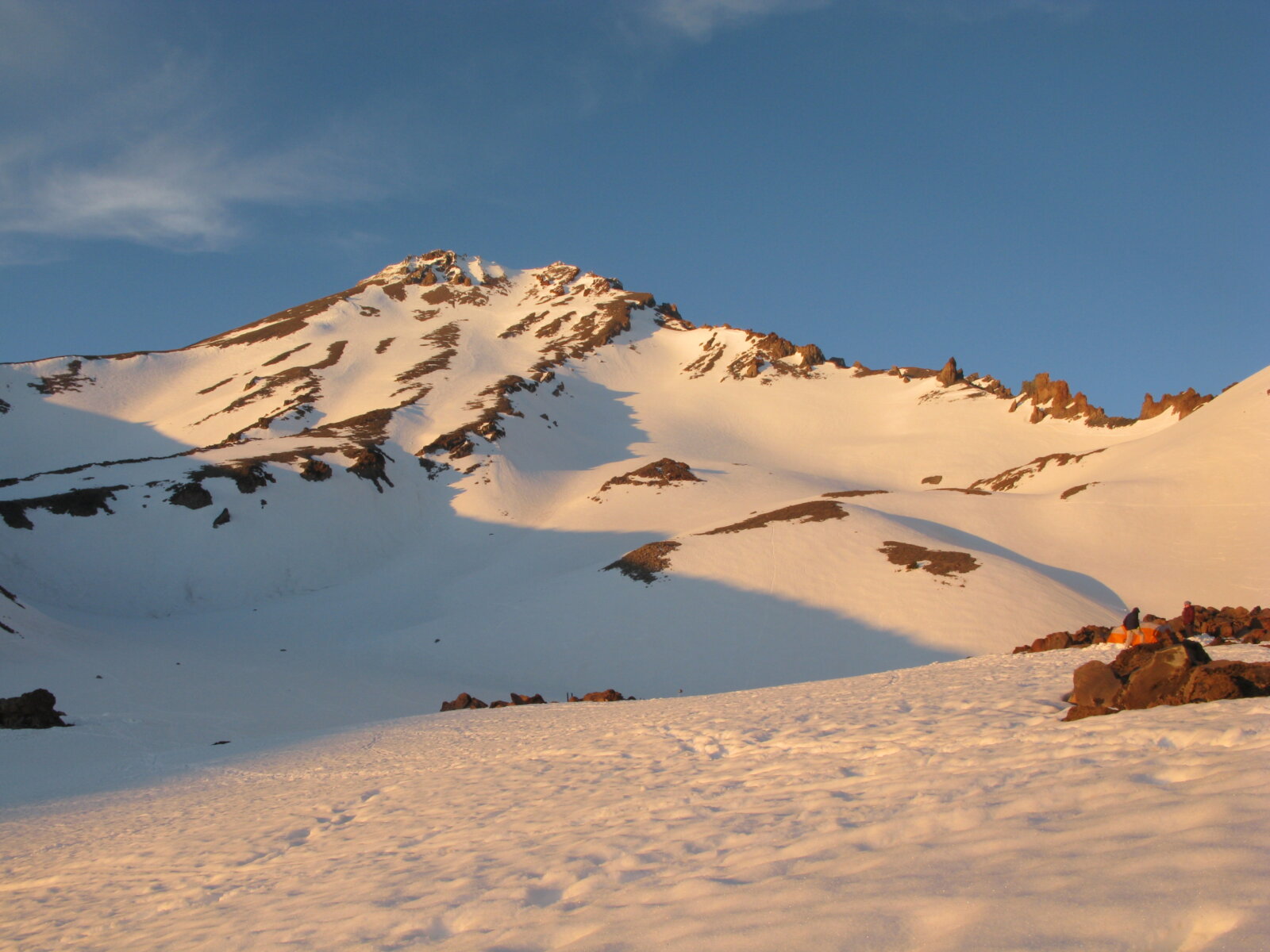 An early morning photo of mount Shasta covered in snow with a blue sky above. Climb Mount Shasta with us!