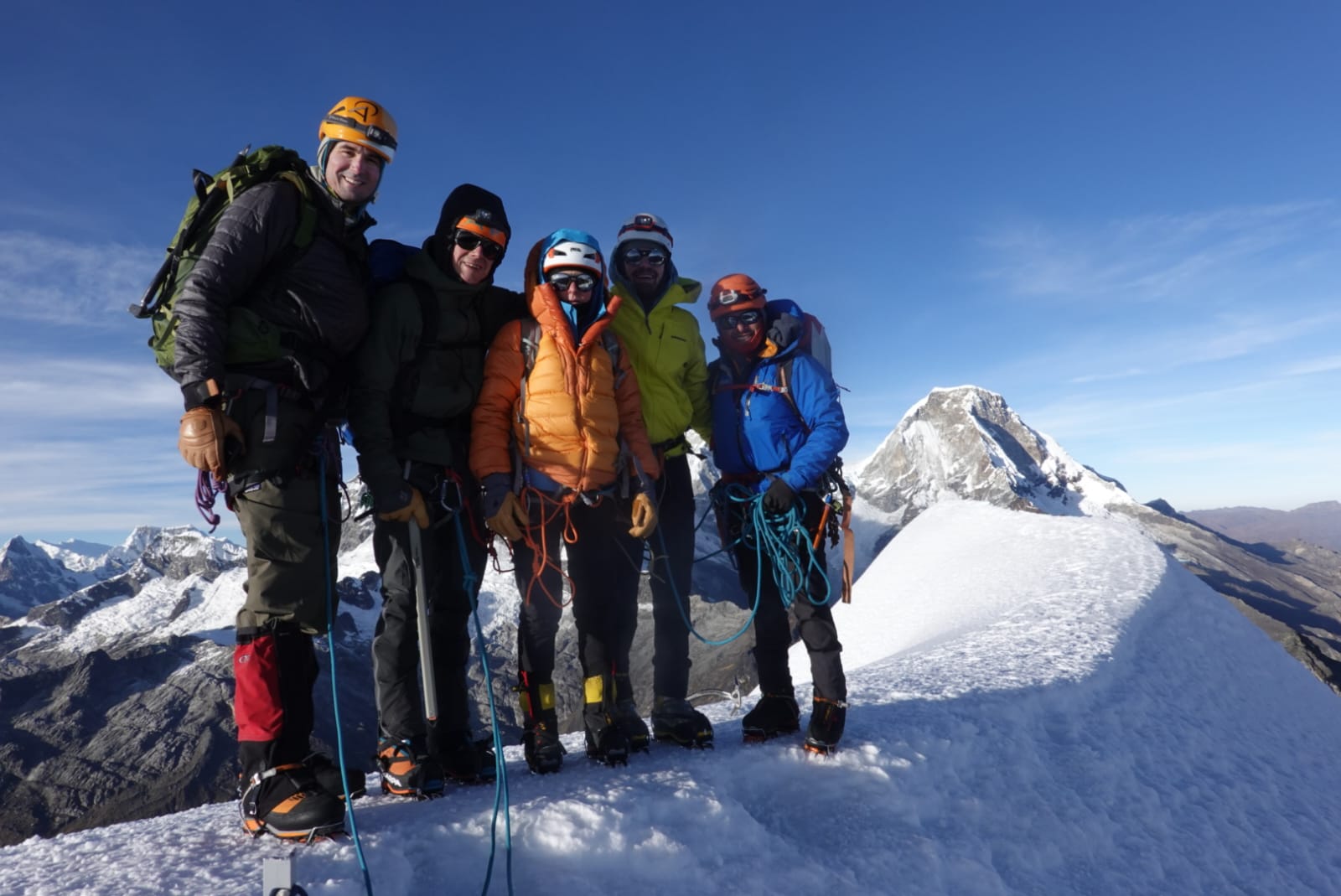A group of 5 mountaineers standing on the summit of a peak in Peru.