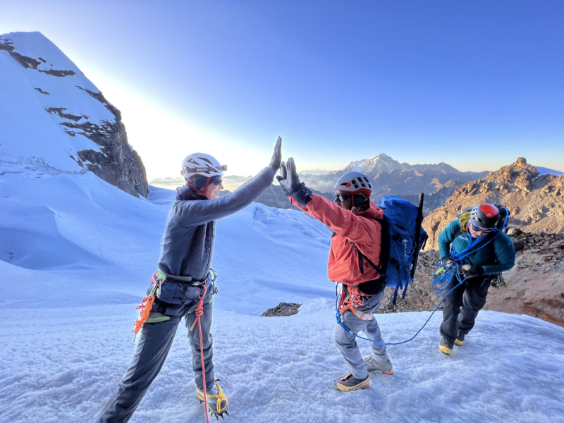two climbers high-five on a glacier in Bolivia
