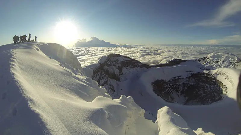 Climbers stand on the summit crater after climbing Cotopaxi.