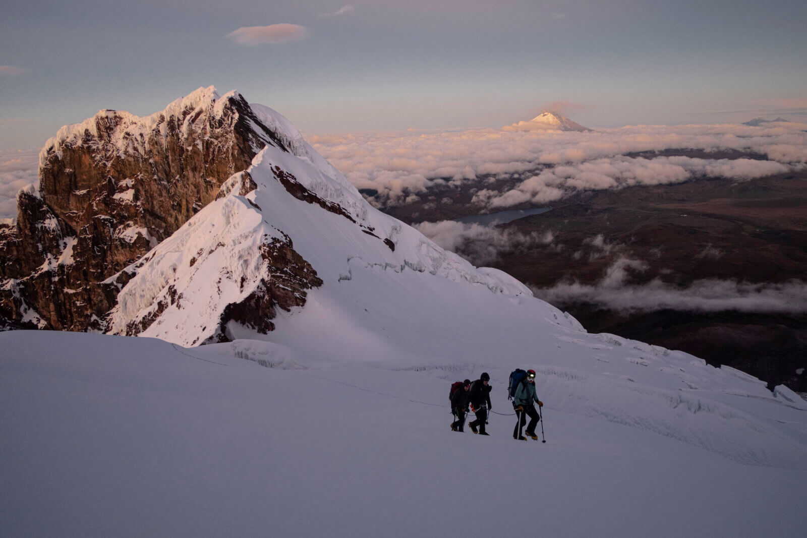 Climbers learning high-altitude mountaineering skills on a volcano in Ecuador at sunrise as part of Alpenglow Expedition's Ecuador Climbing School.