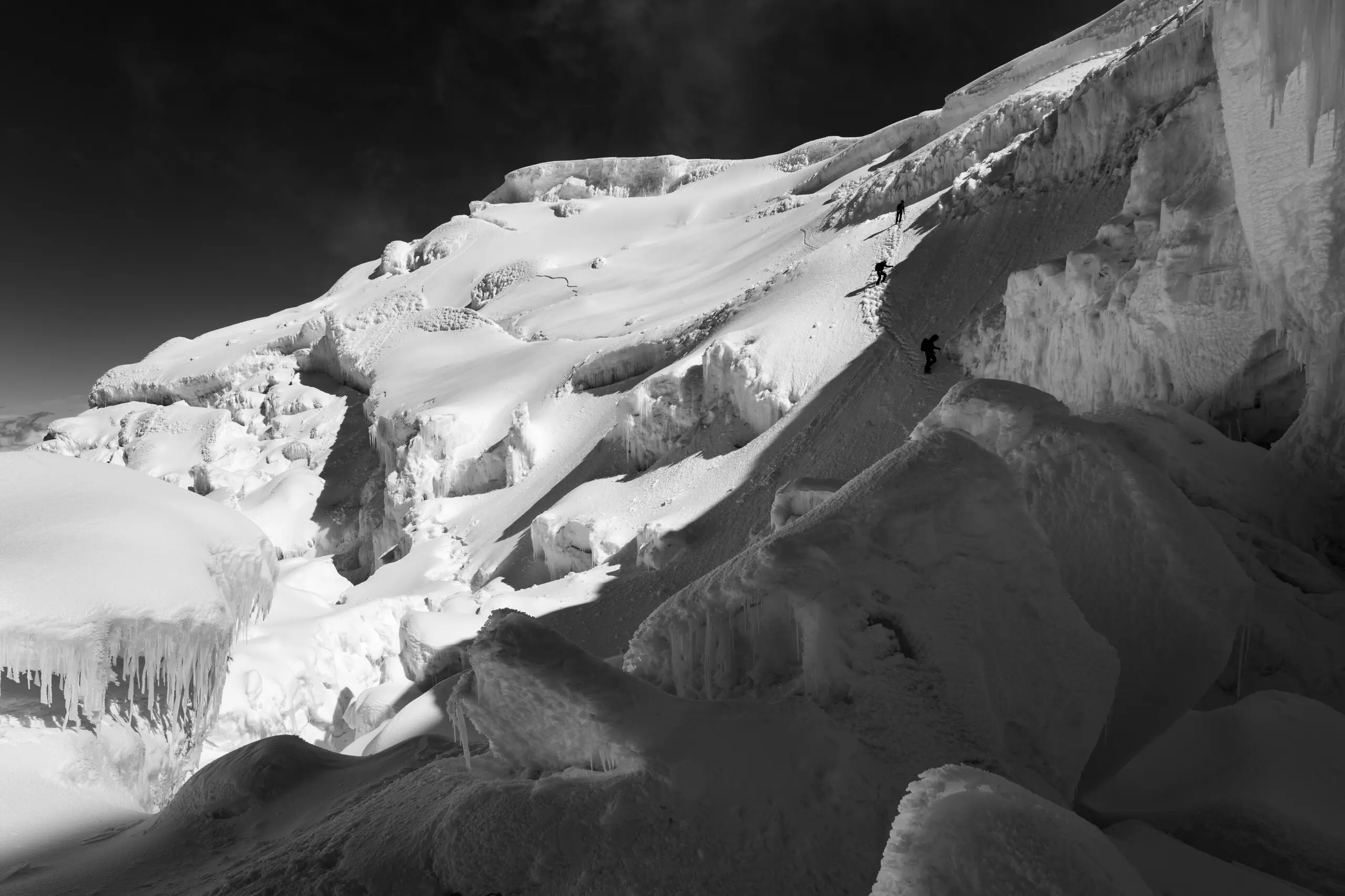 Climbers descend from the summit of Antisana approaching a hanging serac.