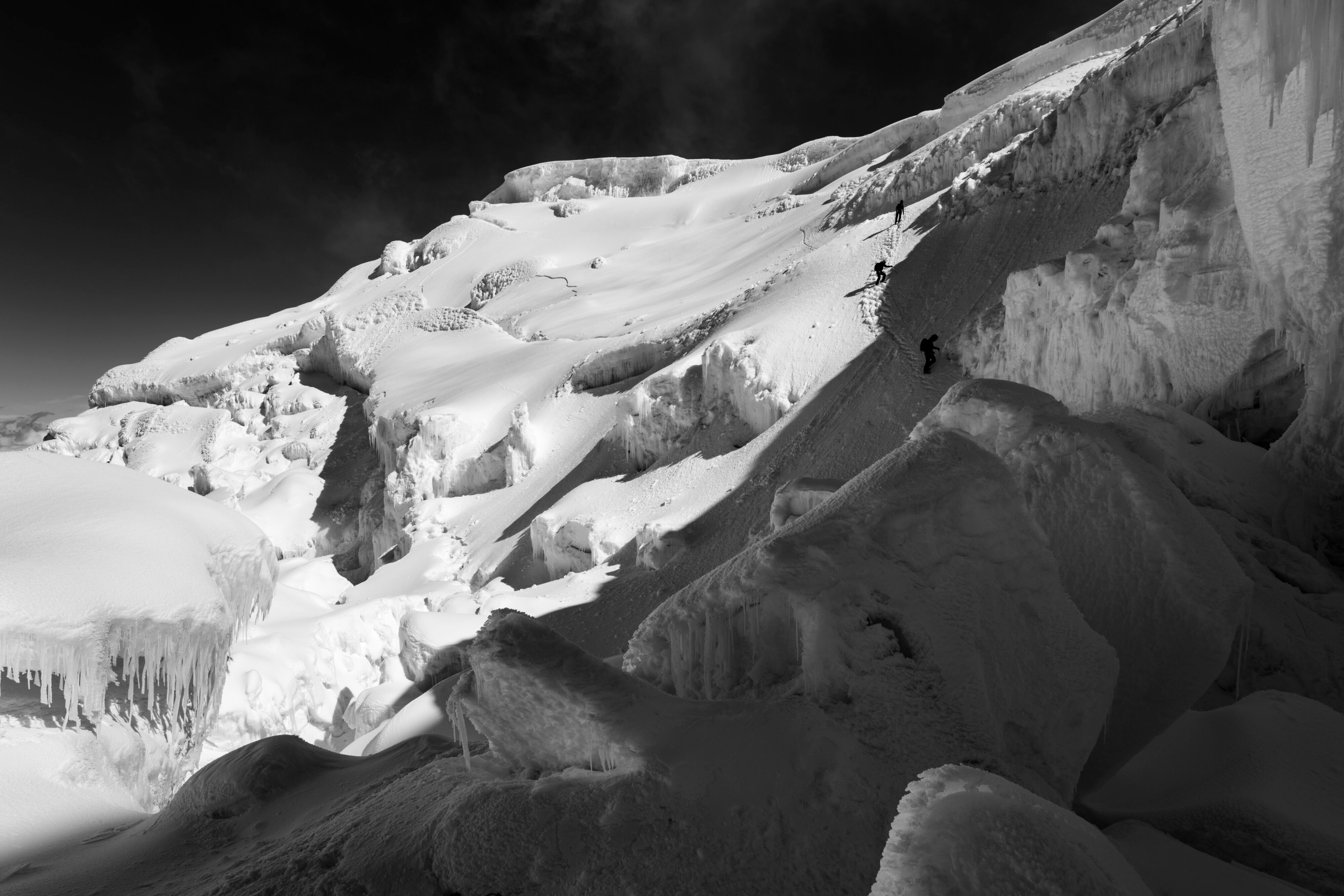 Climbers descend from the summit of Antisana approaching a hanging serac. 