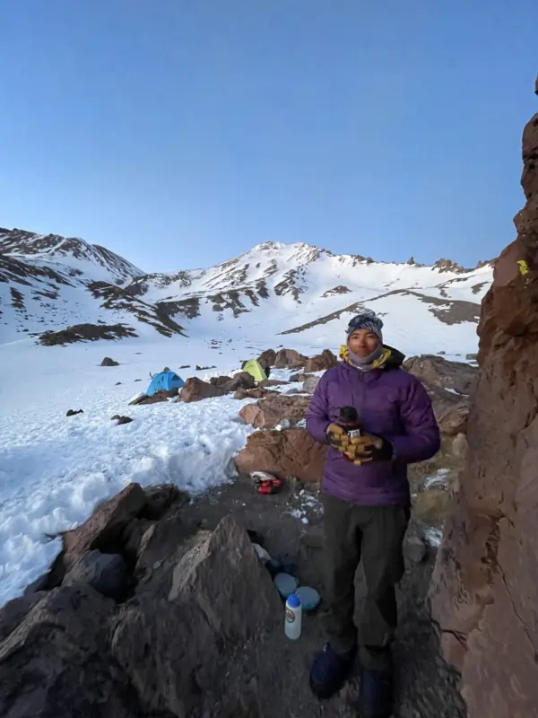 Ski guide Isaac Laredo stands in front of a tent on Mount Shasta