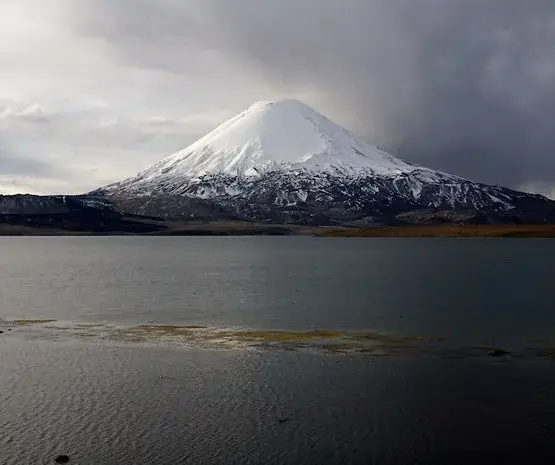 Acotango, a large snow covered volcano overlooking a big lake. 