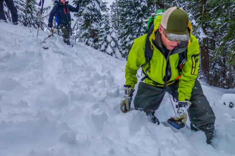 A skier practicing a beacon locating drill during avalanche rescue training with Alpenglow Expeditions.
