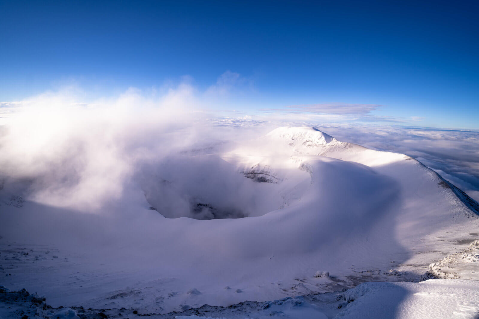 The summit of Cotopaxi volcano shrouded in clouds and mist during a guided Cotopaxi Expedition with Alpenglow Expeditions.