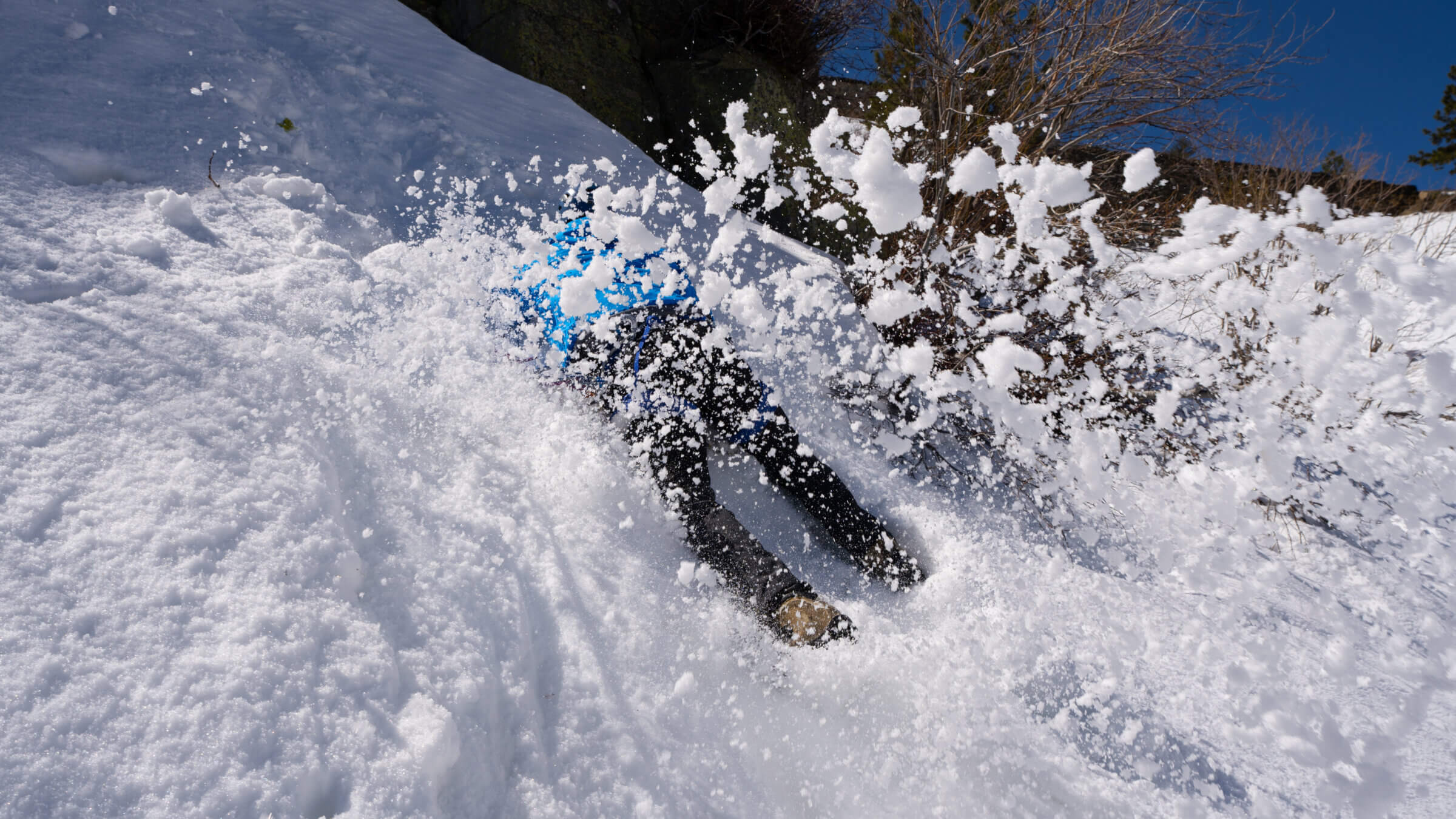 A climber practices self arrest, spraying the lens with clumps of snow.