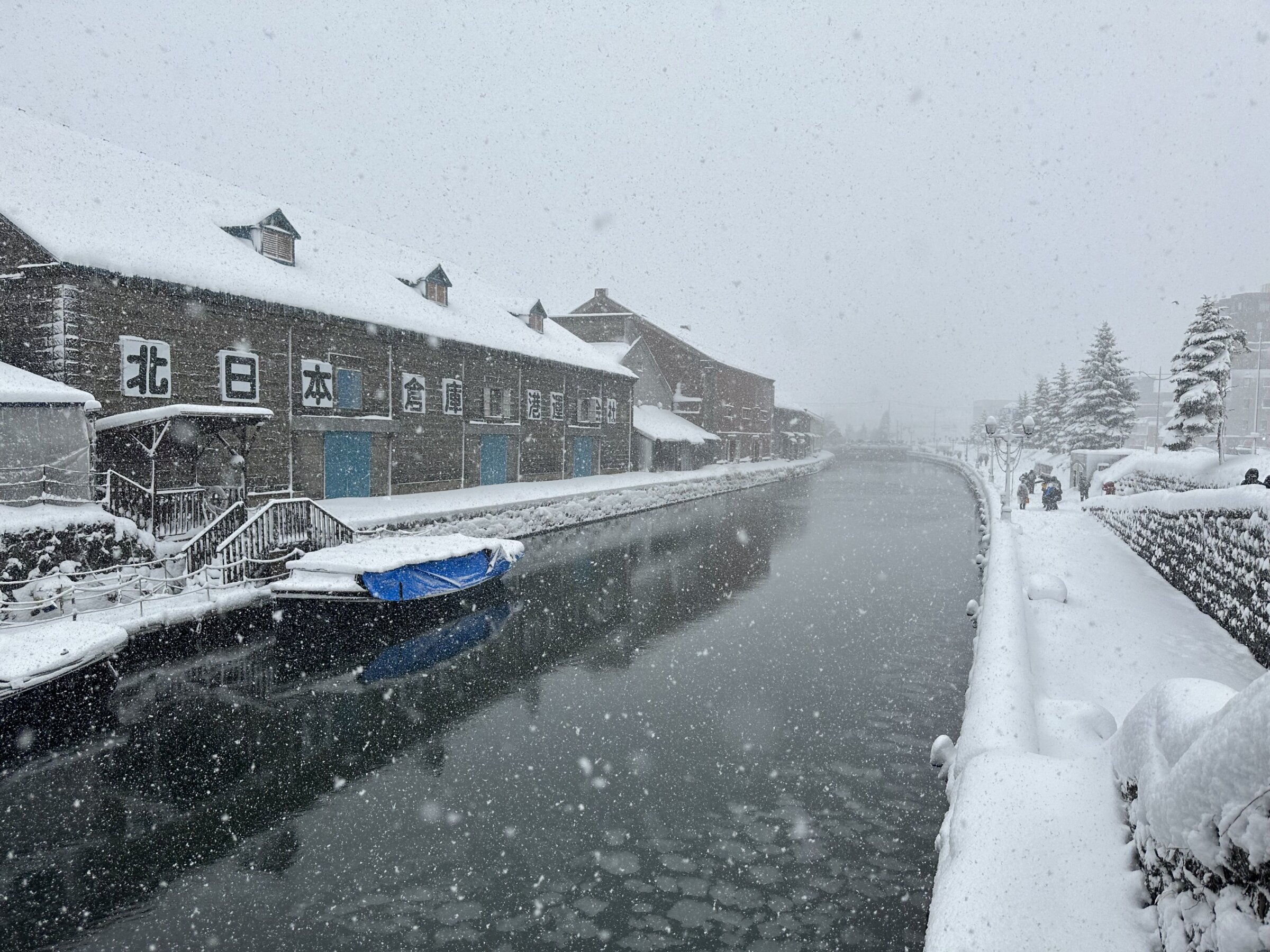 A snowy canal in Japan with dark water and short buildings during a guided Japan ski trip with Alpenglow Expeditions.