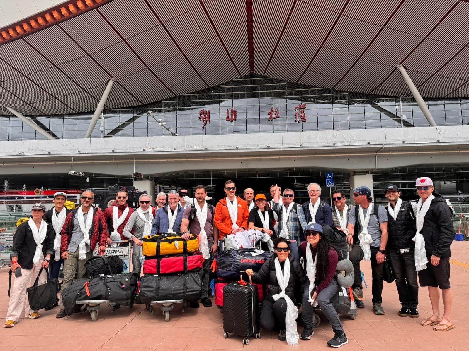 A group of climbers stand in front of the entrance to the airport in Lhasa, Tibet with their luggage on the way to the north side of Mt. Everest.