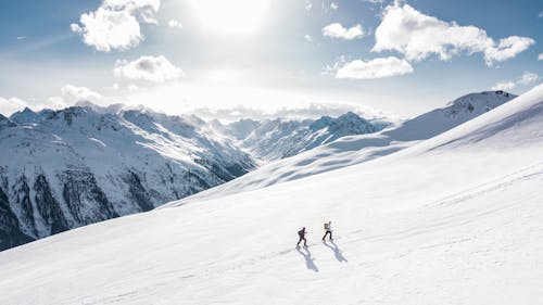 two backcountry skiers in Japan tour uphill on a vast white slope with the mountains spread behind them