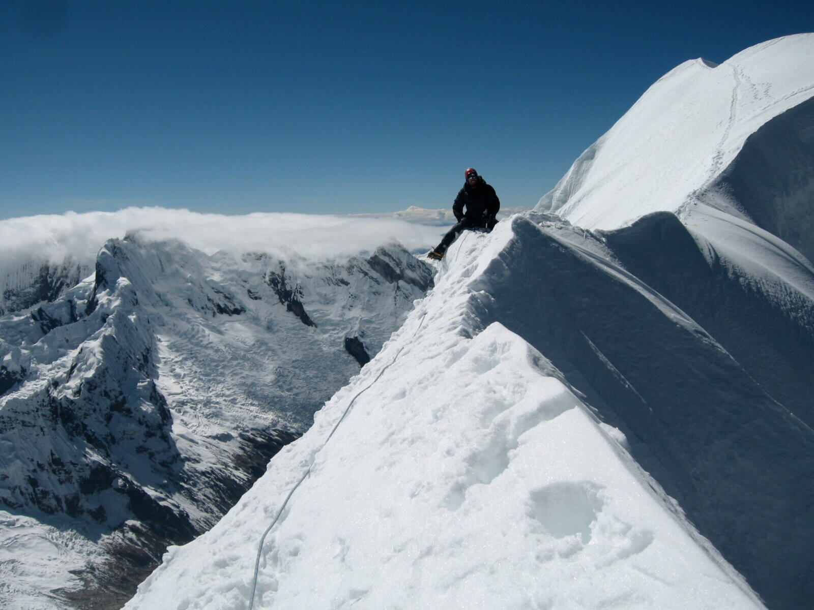 Client sitting on a ridge on Quitaraju in Peru with Alpenglow Expeditions