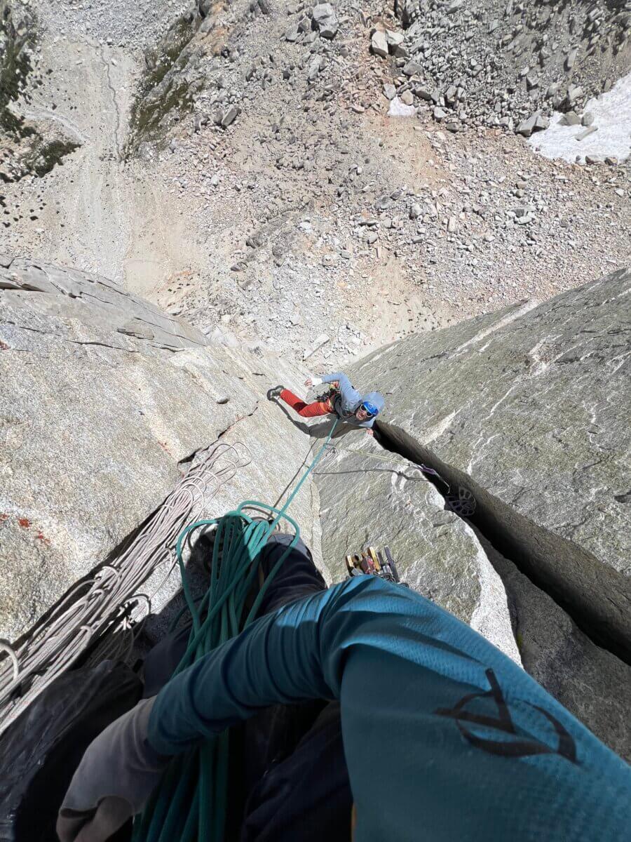 a top down view of a climbing guide belaying a climber on a steep granite crack